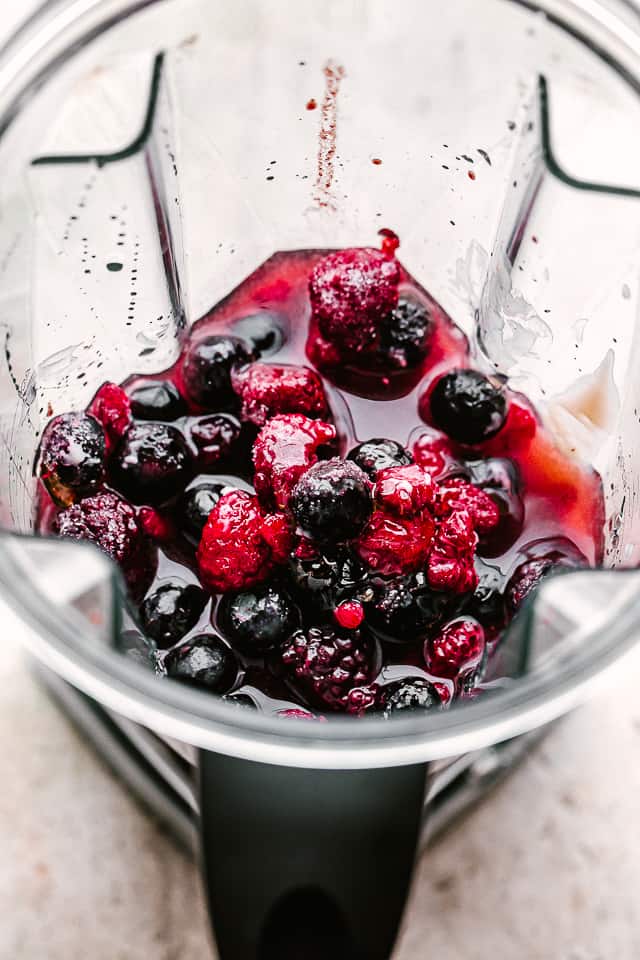 Blending frozen berries in a blender.