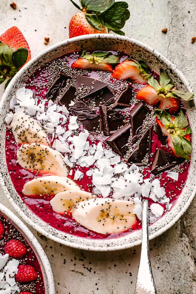 An acai bowl topped with fruit, coconut flakes, and chocolate.