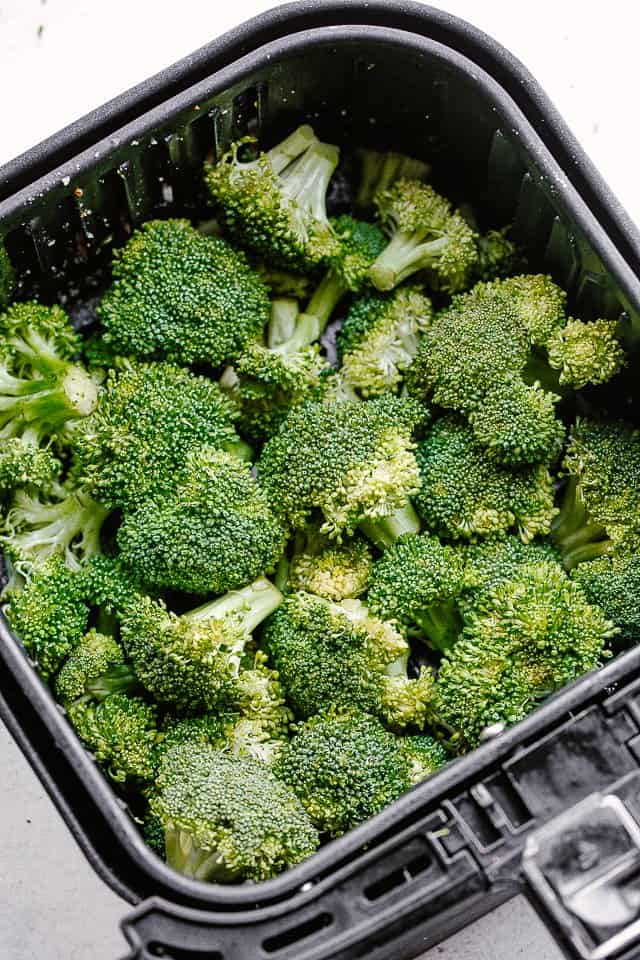 fresh broccoli florets in black air fryer basket