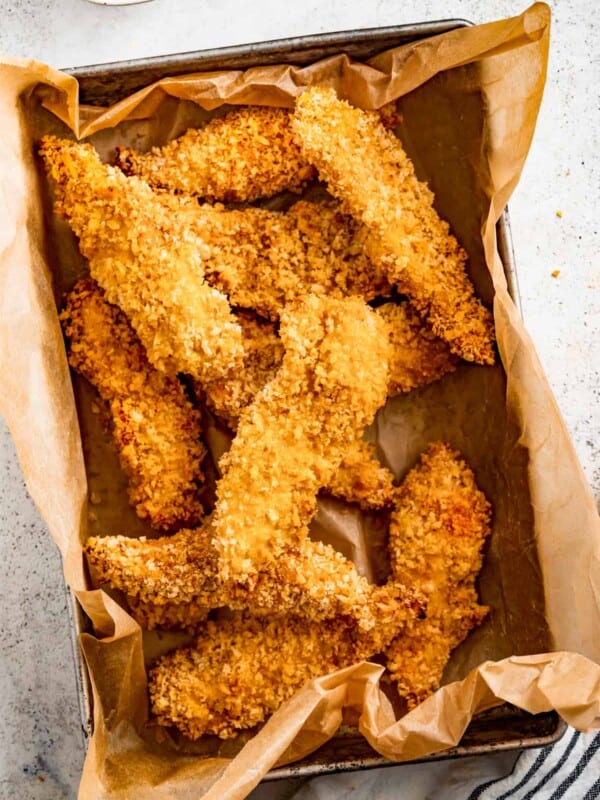 Air fryer chicken tenders in a paper-lined container.