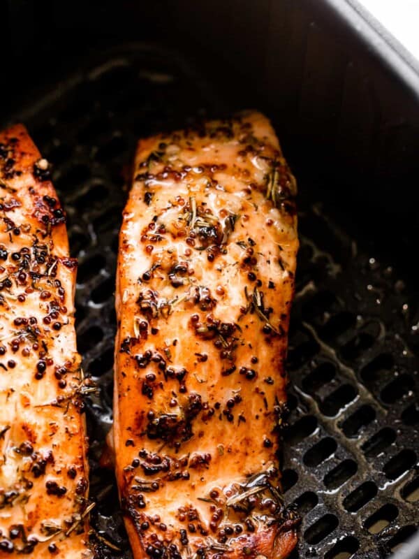 two seasoned salmon fillets in a black air fryer basket.