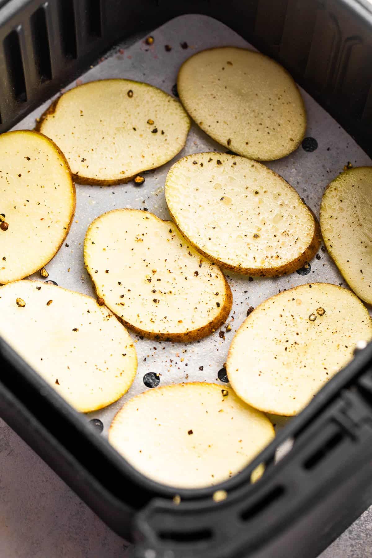 raw potato slices in an air fryer basket