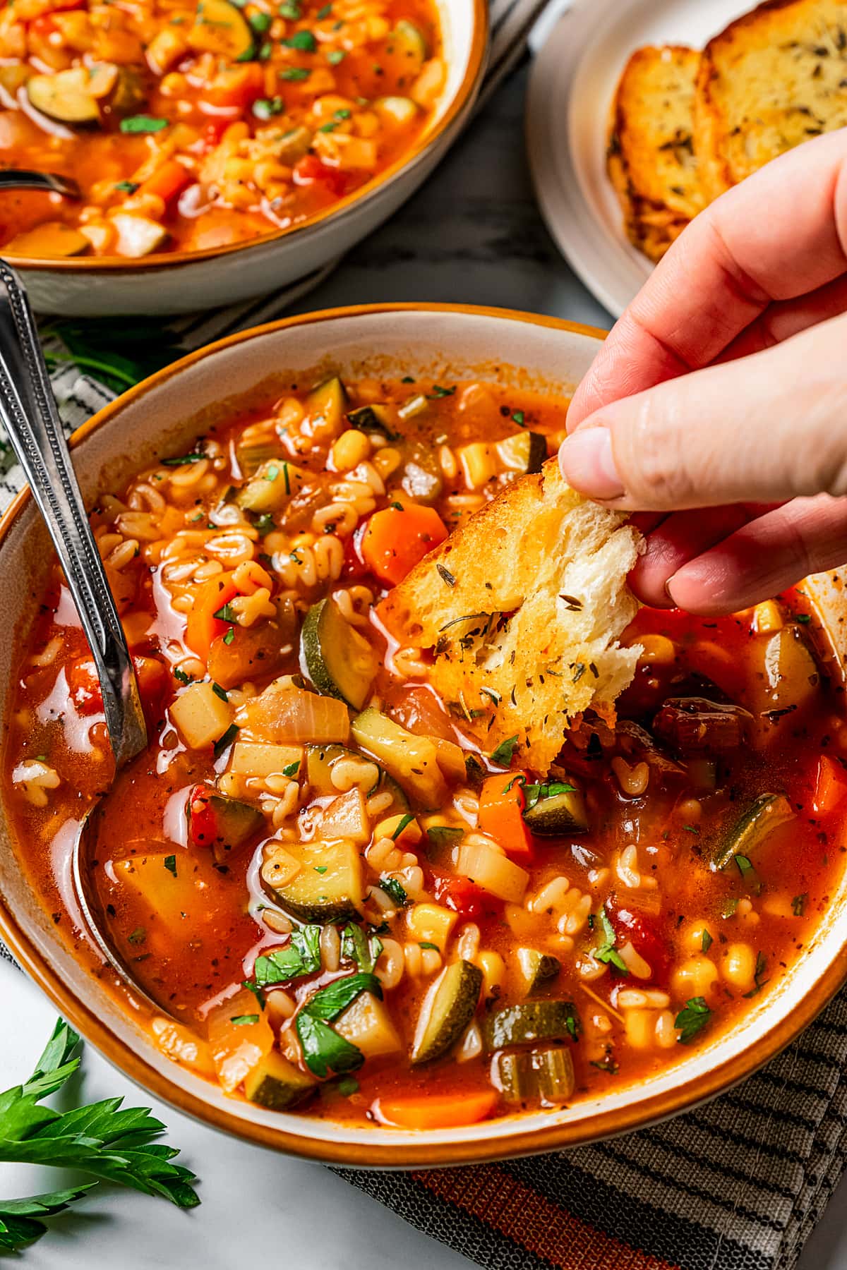 Dipping garlic bread into a bowl of soup.