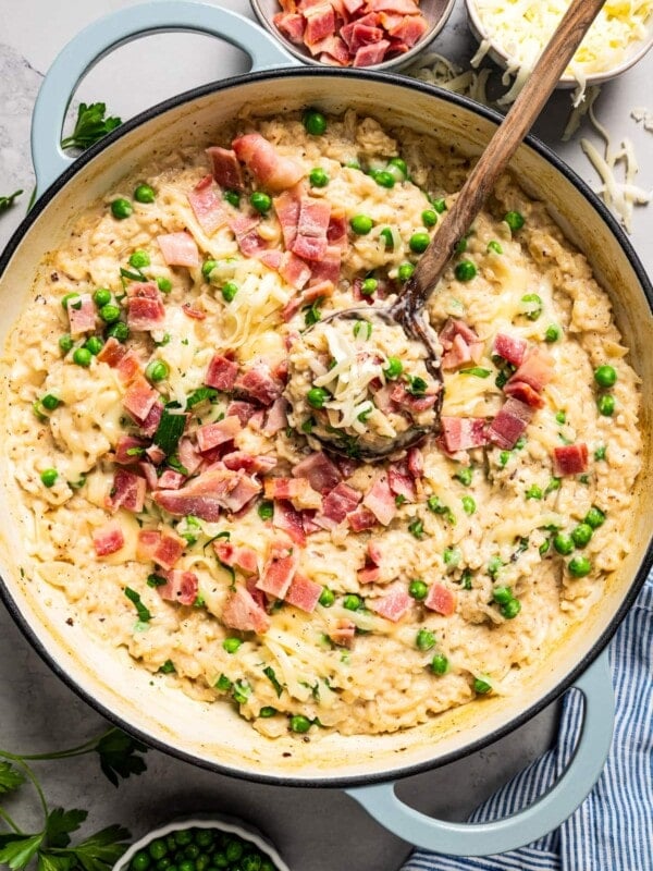 Stirring through risotto topped with bacon and peas.