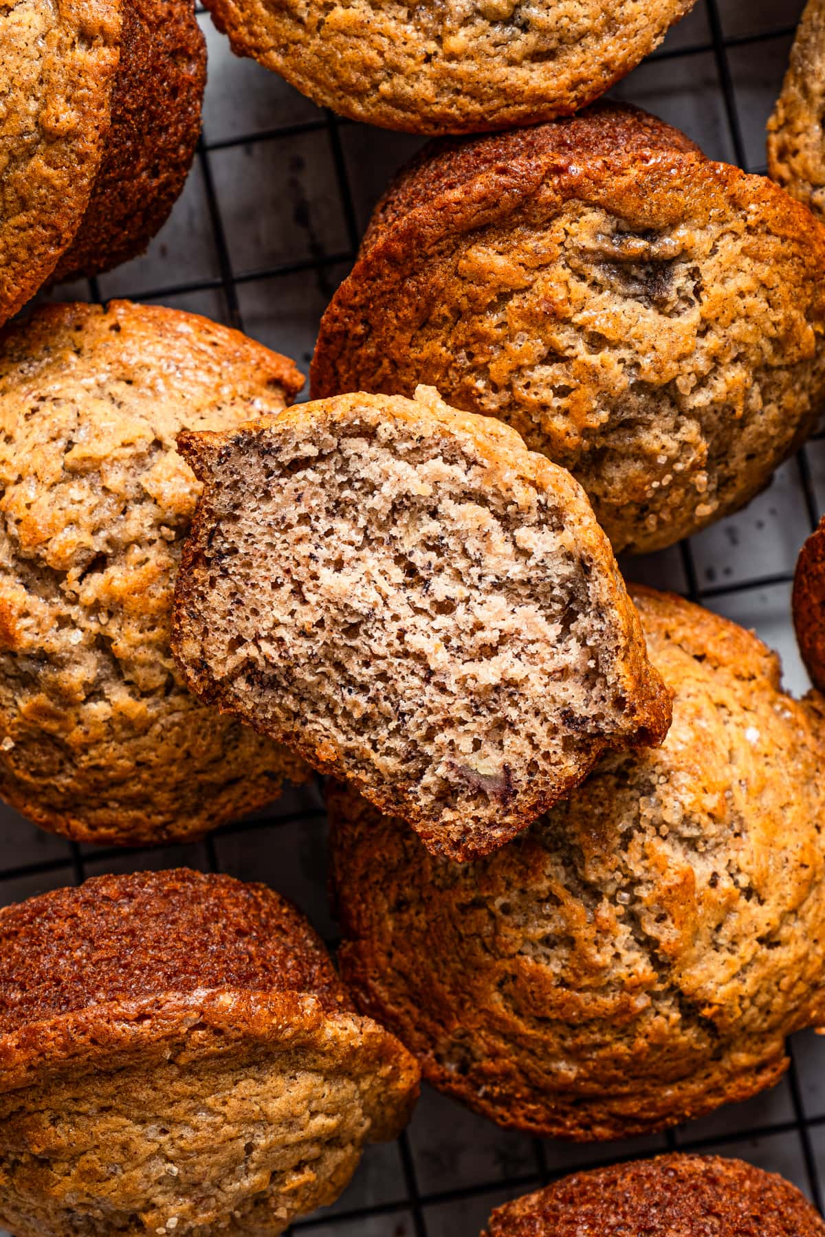 Banana walnut muffins on a cooling rack. One is cut in half.