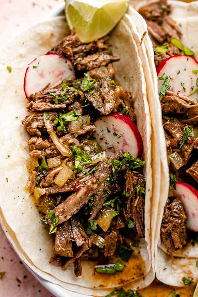 Close up of barbacoa beef tacos topped with with radishes.