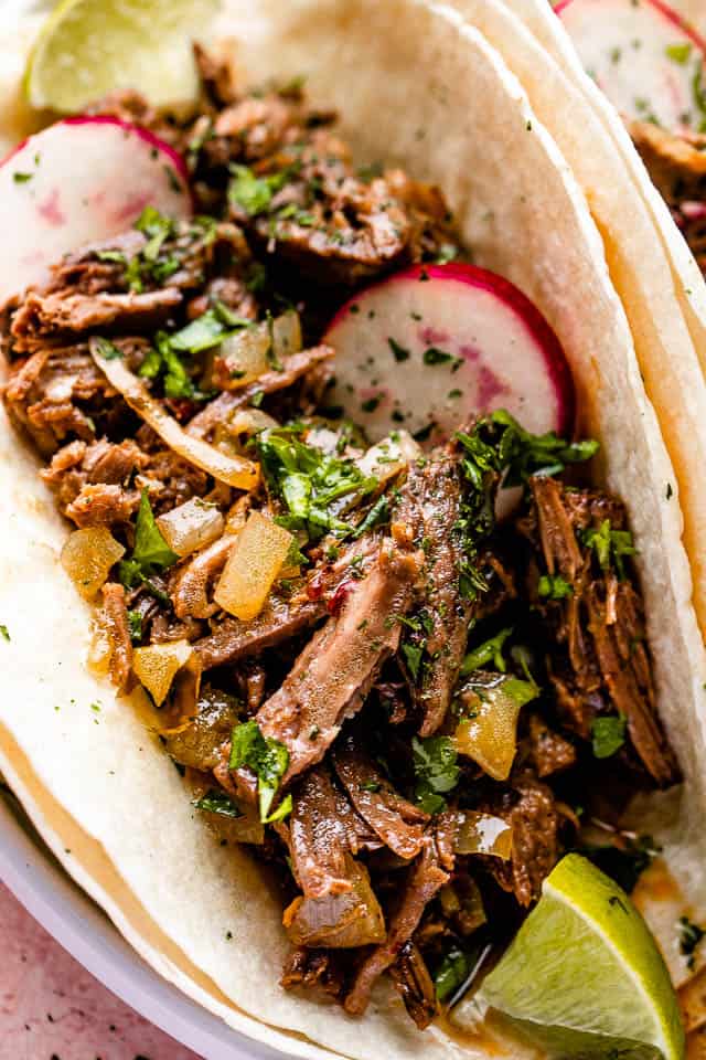 Close up of barbacoa beef tacos topped with with radishes.