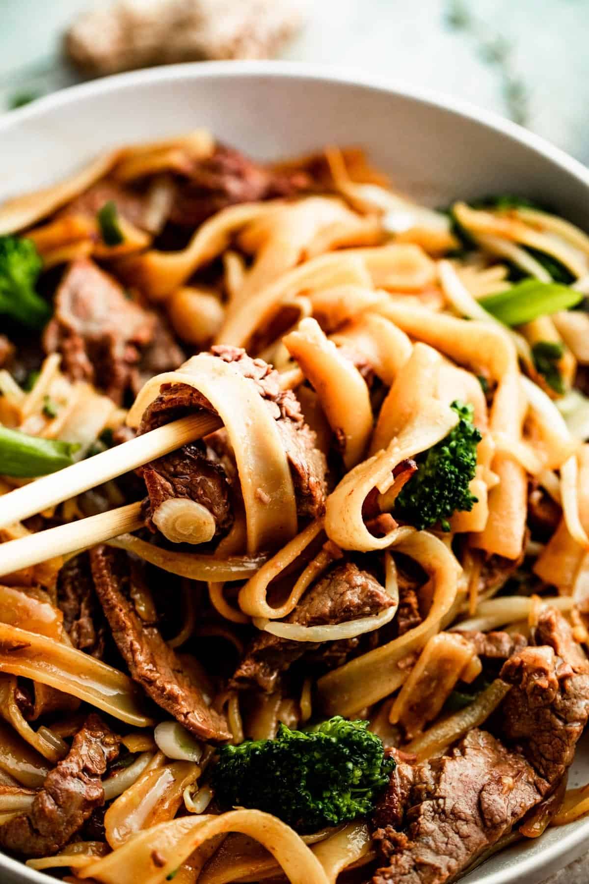 overhead shot of chopsticks rotating beef chow fun.