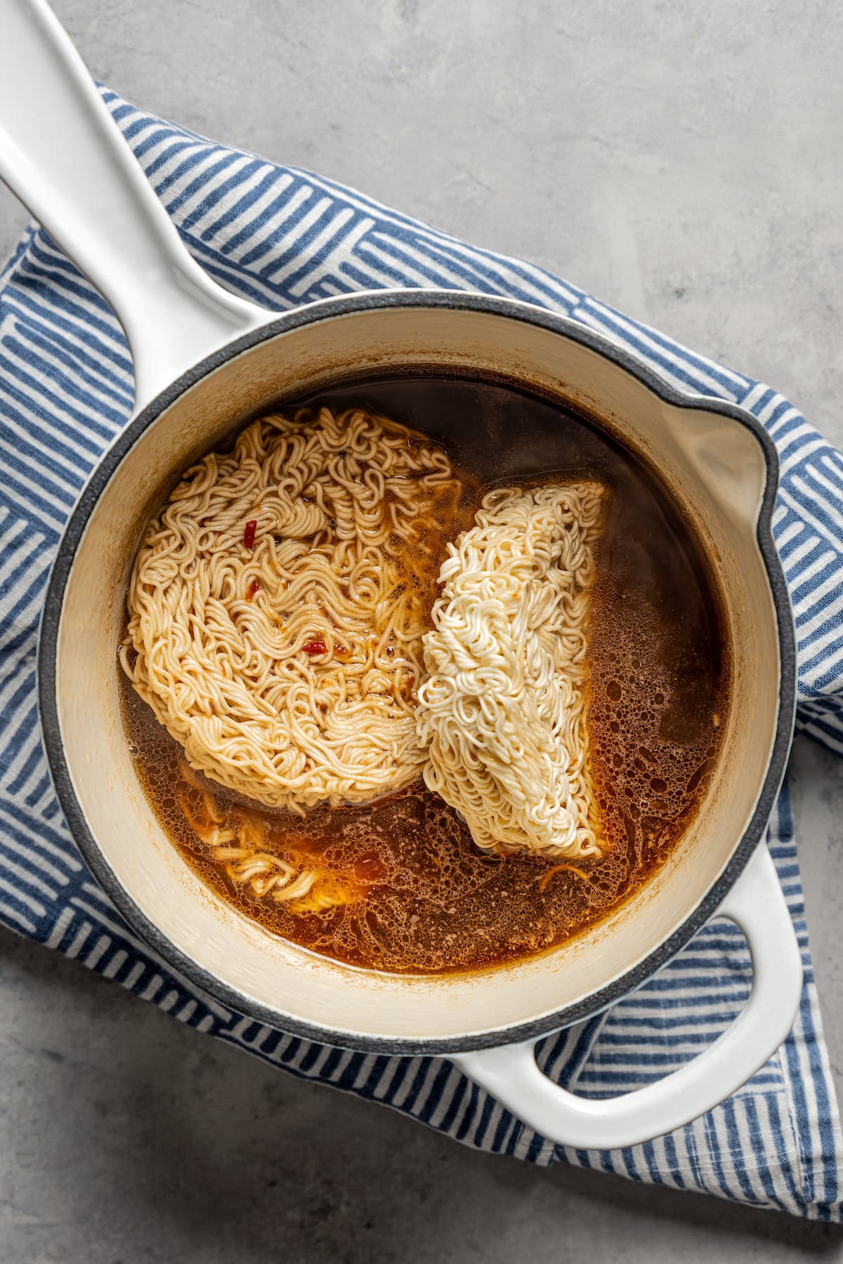 Ramen noodle nests added into a pot with broth.