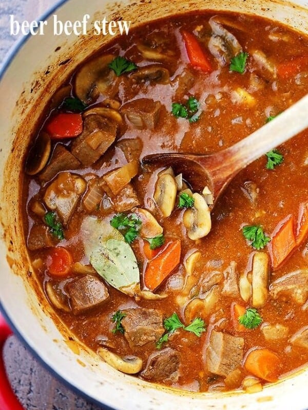 Overhead image of beef stew in a Dutch oven with a wooden spoon stirring through it.