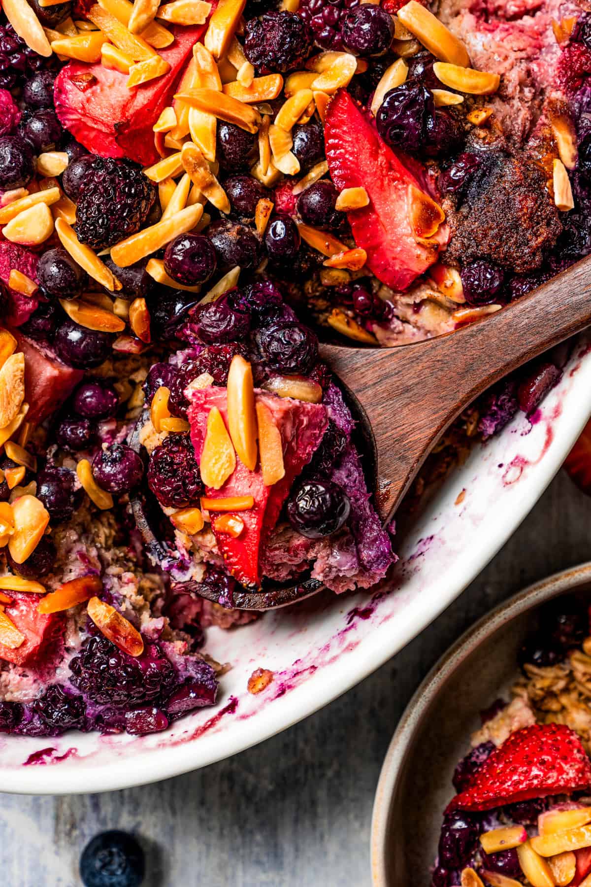 A wooden spoon scooping out baked oatmeal from a baking dish.