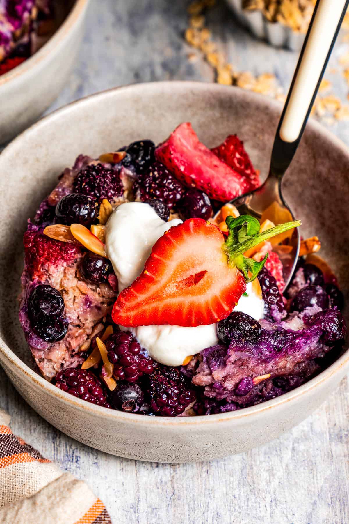 Baked oatmeal served in a bowl with a garnish of whipped cream and fresh strawberries.