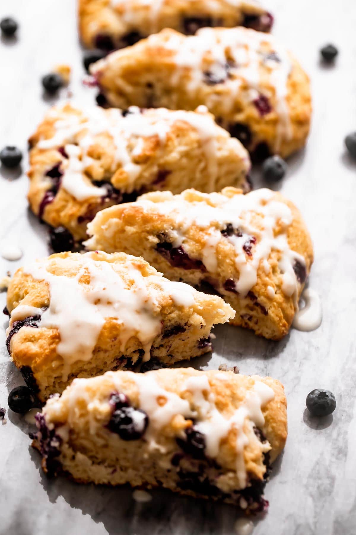 Scones arranged on a table, and blueberries scattered around them.