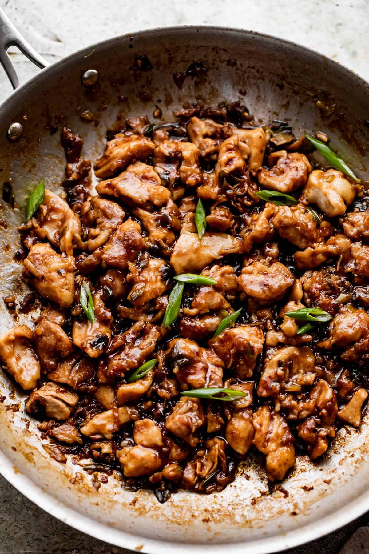 photo of a skillet while cooking cut up chicken thighs in bourbon sauce.