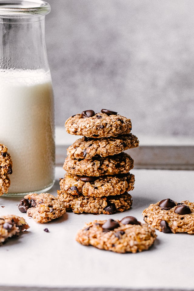 Banana oats chocolate chip cookies stacked next to a milk jug.