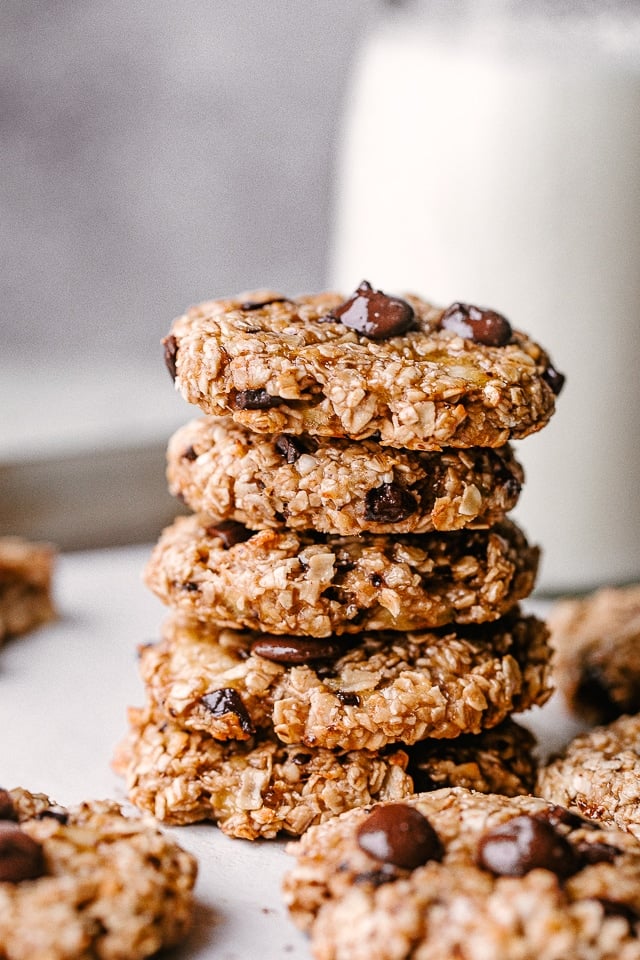 A stack of banana chocolate chip cookies with a milk carafe in the background.