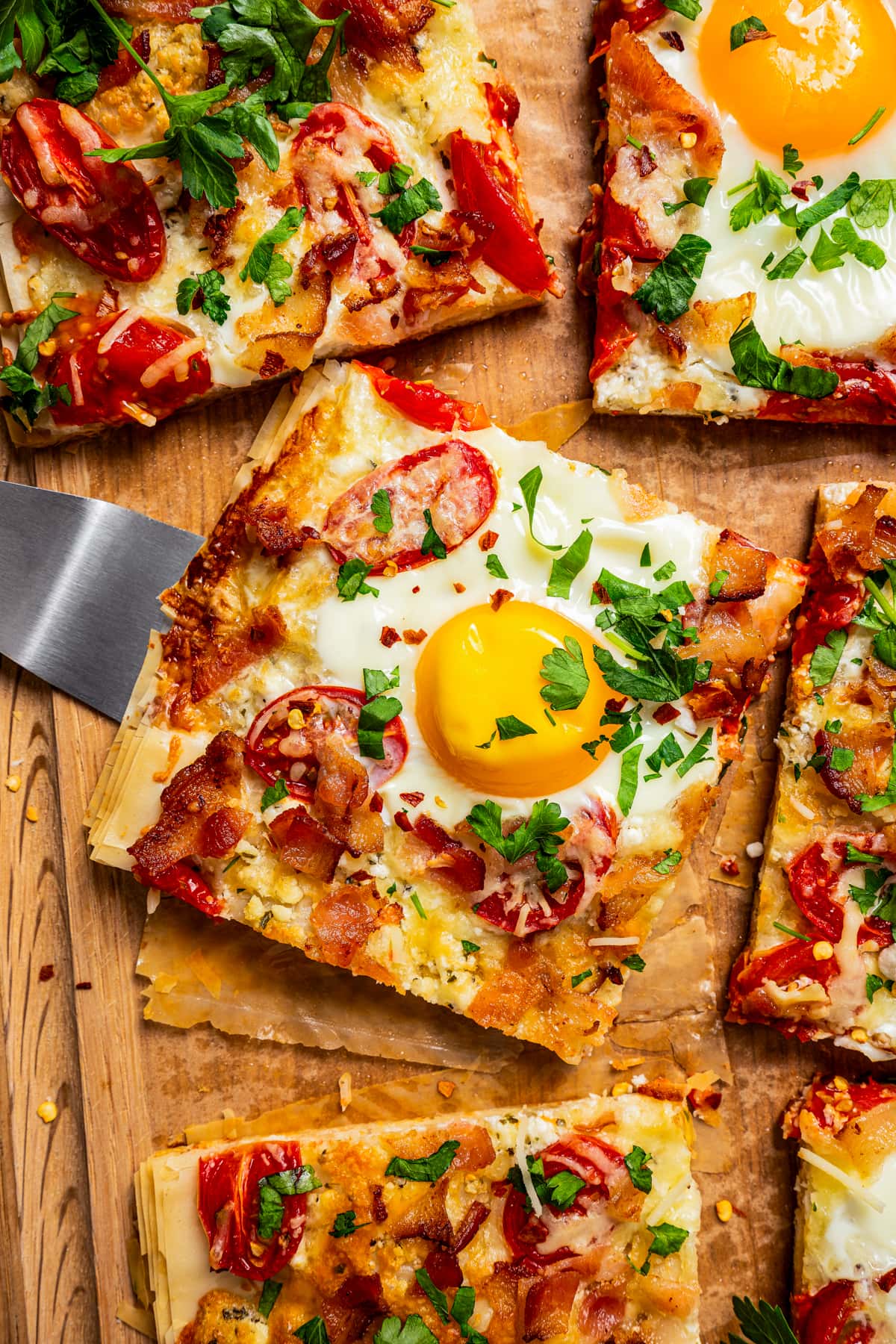 Sliced breakfast pizza with a soft-set egg, tomatoes, and feta cheese.