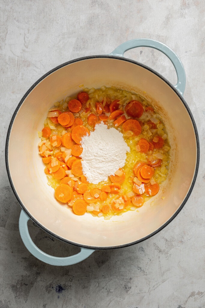 Adding butter and flour to a soup oit with sauteed veggies to make a roux.