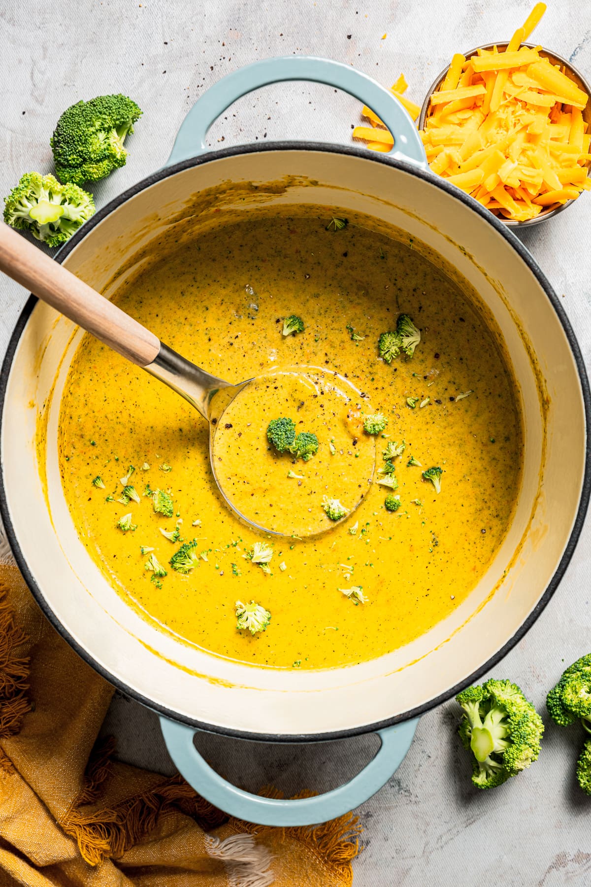 Overhead image of broccoli cheese soup in a soup pot with a ladle.