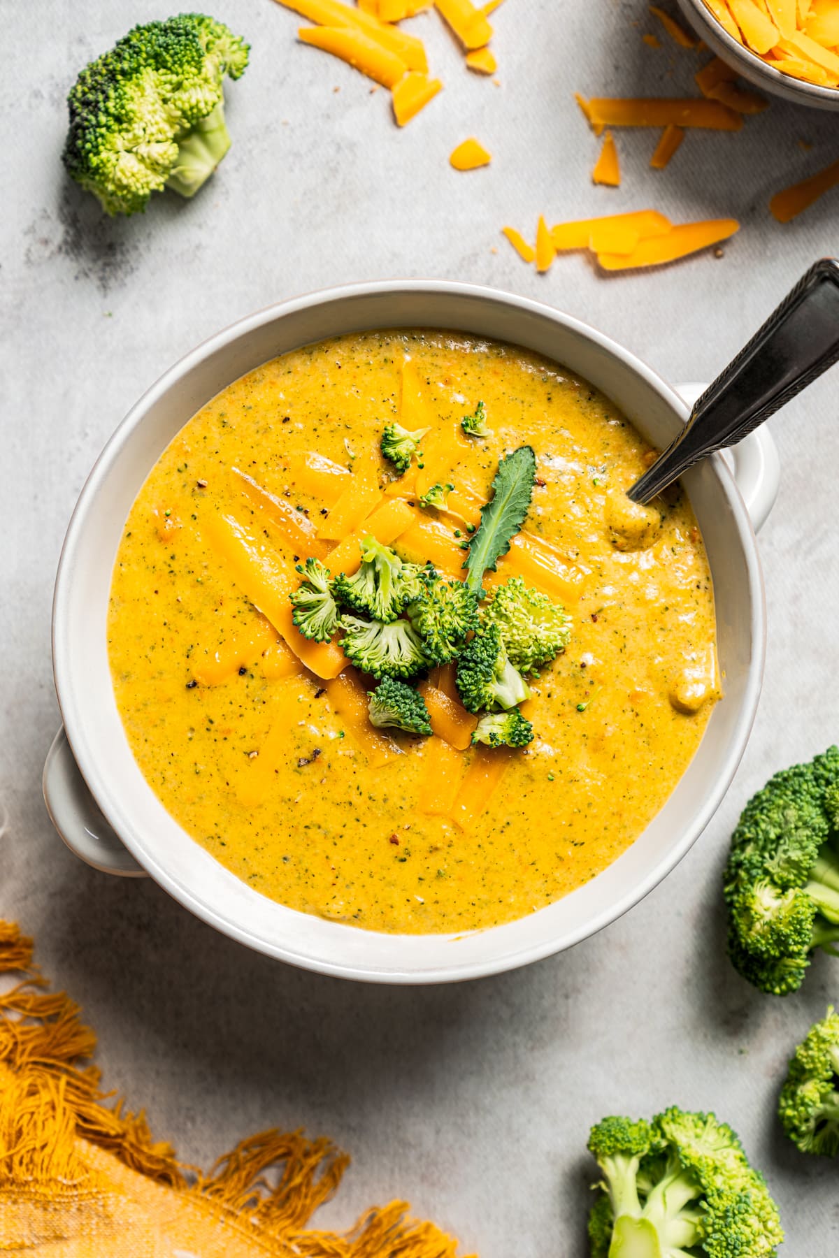 Overhead image of broccoli cheese soup in a bowl with a spoon.