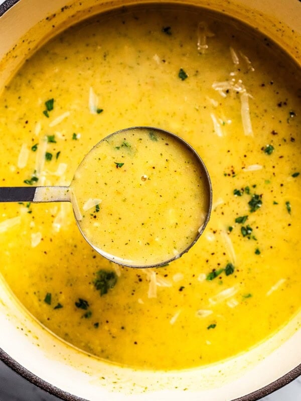 A ladle full of broccoli potato soup held over a pot.