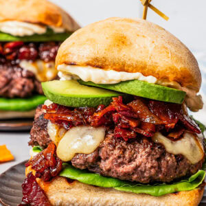 Close up of an assembled California burger on a brown stoneware plate.