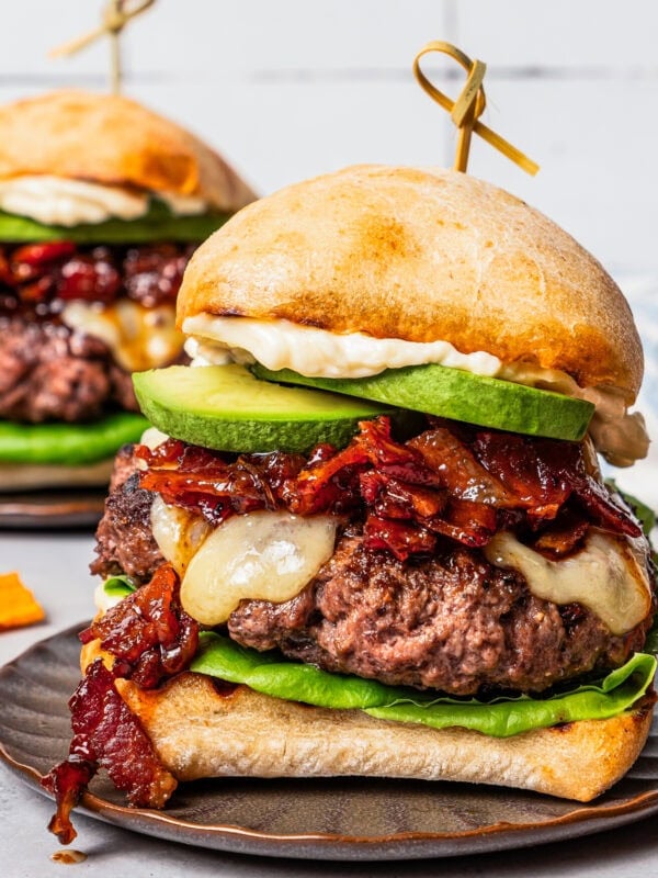 Close up of an assembled California burger on a brown stoneware plate.