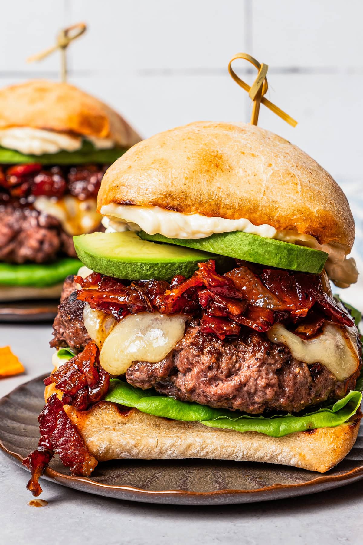 Close up of an assembled California burger on a brown stoneware plate.