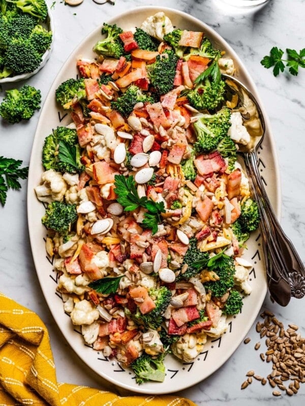 Overhead image of broccoli cauliflower salad on a serving plate with a serving spoon.