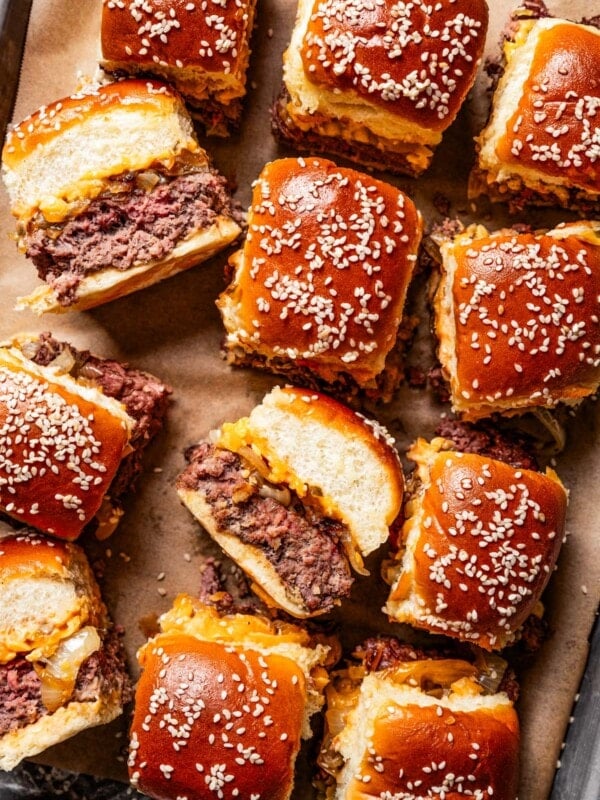 Cheeseburger sliders arranged on a sheet pan lined with parchment paper.