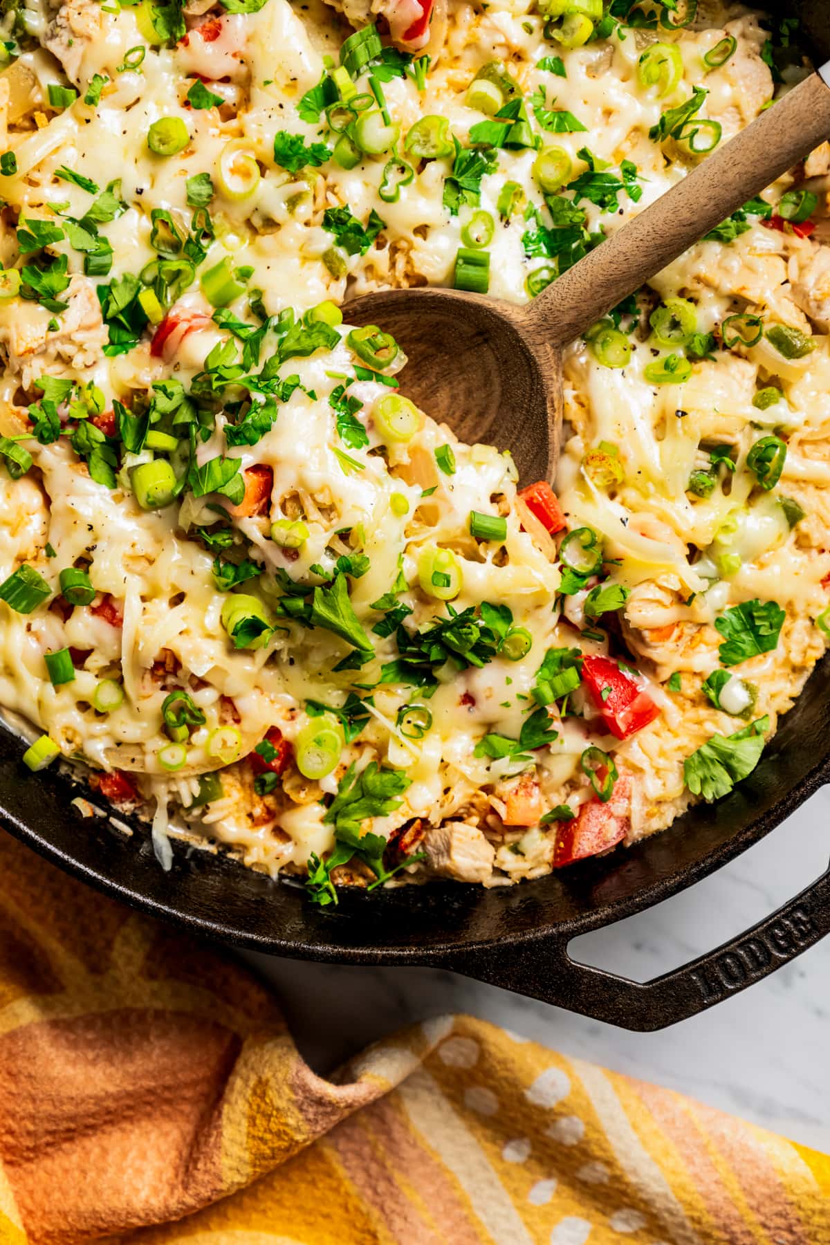 Overhead image of a wooden spoon scooping chicken and rice out of a skillet.