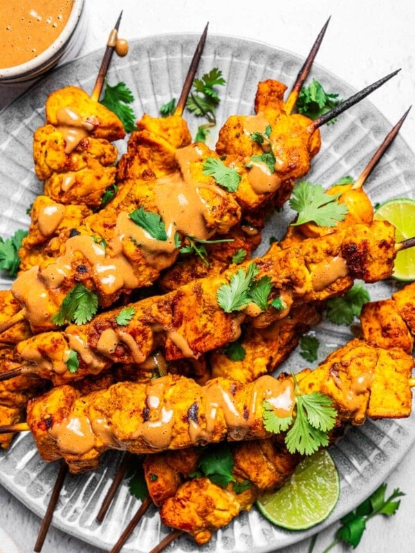 Overhead of chicken satay near a bowl of peanut dipping sauce