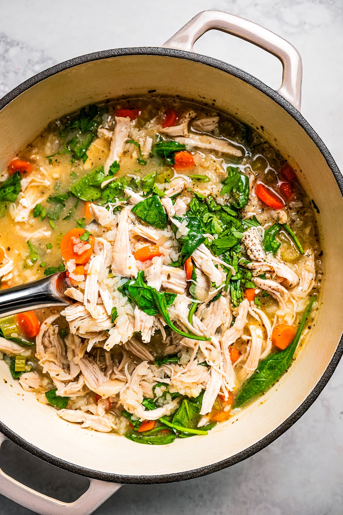 Ladling chicken veggie soup out of a soup pot.