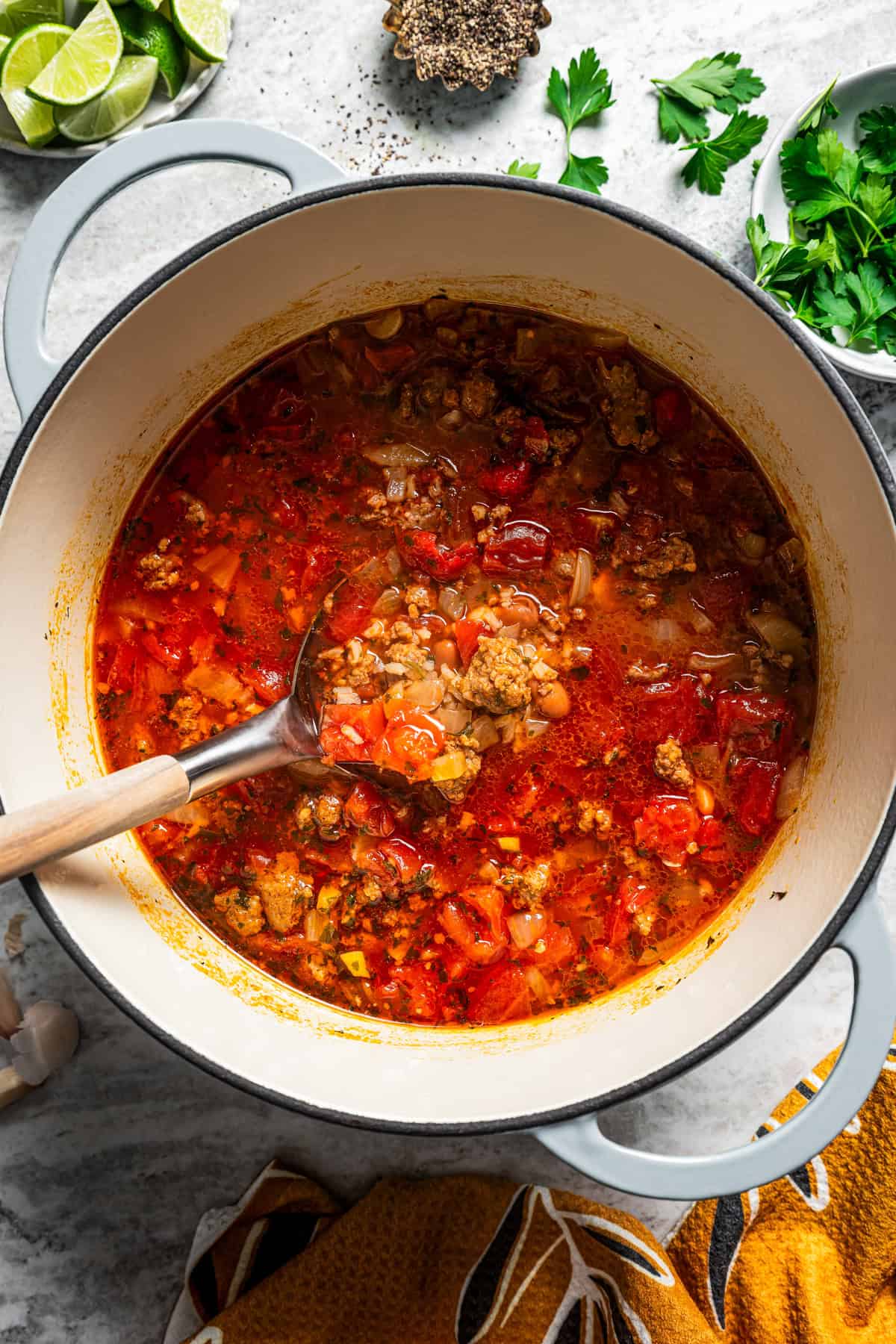 A spoon resting in a pot of chorizo soup.