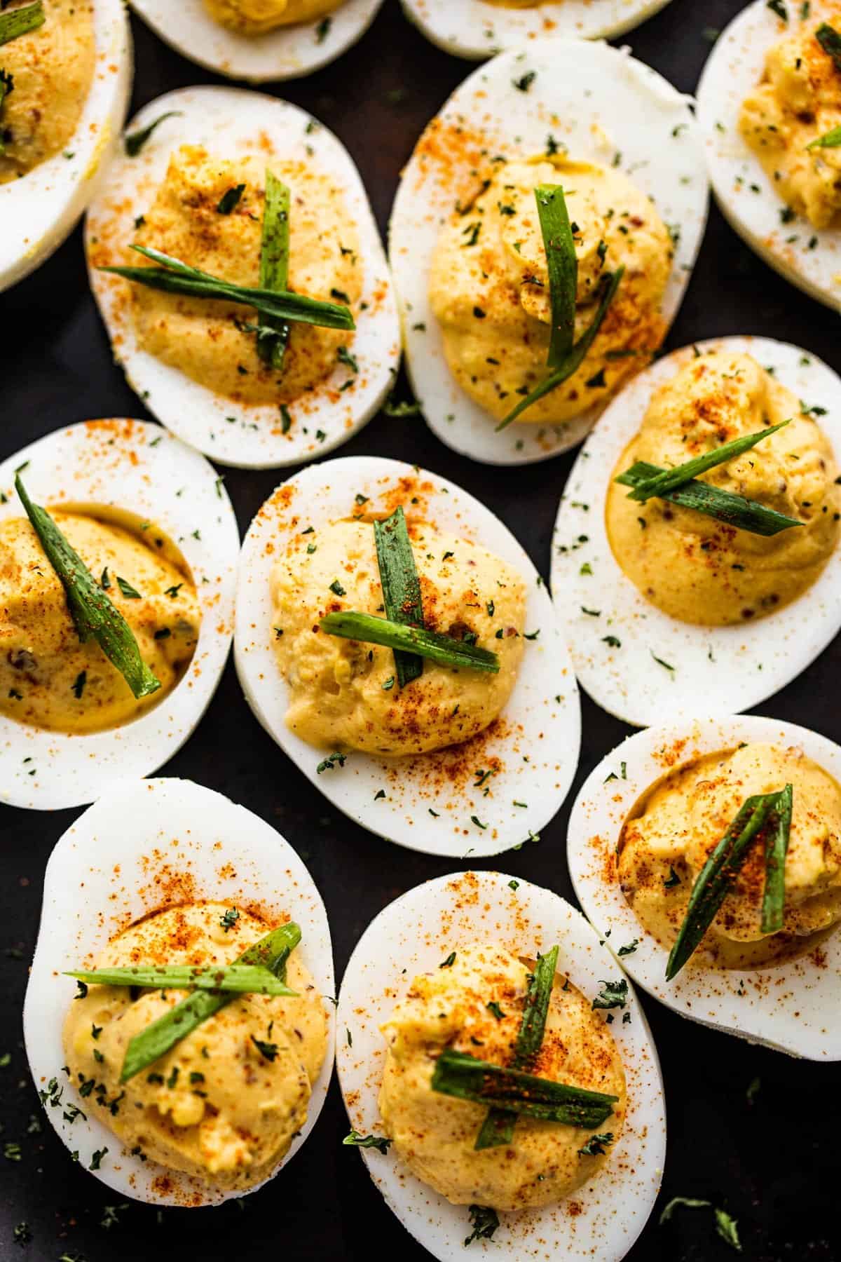 Close-up overhead shot of deviled eggs set on a dark backdrop.