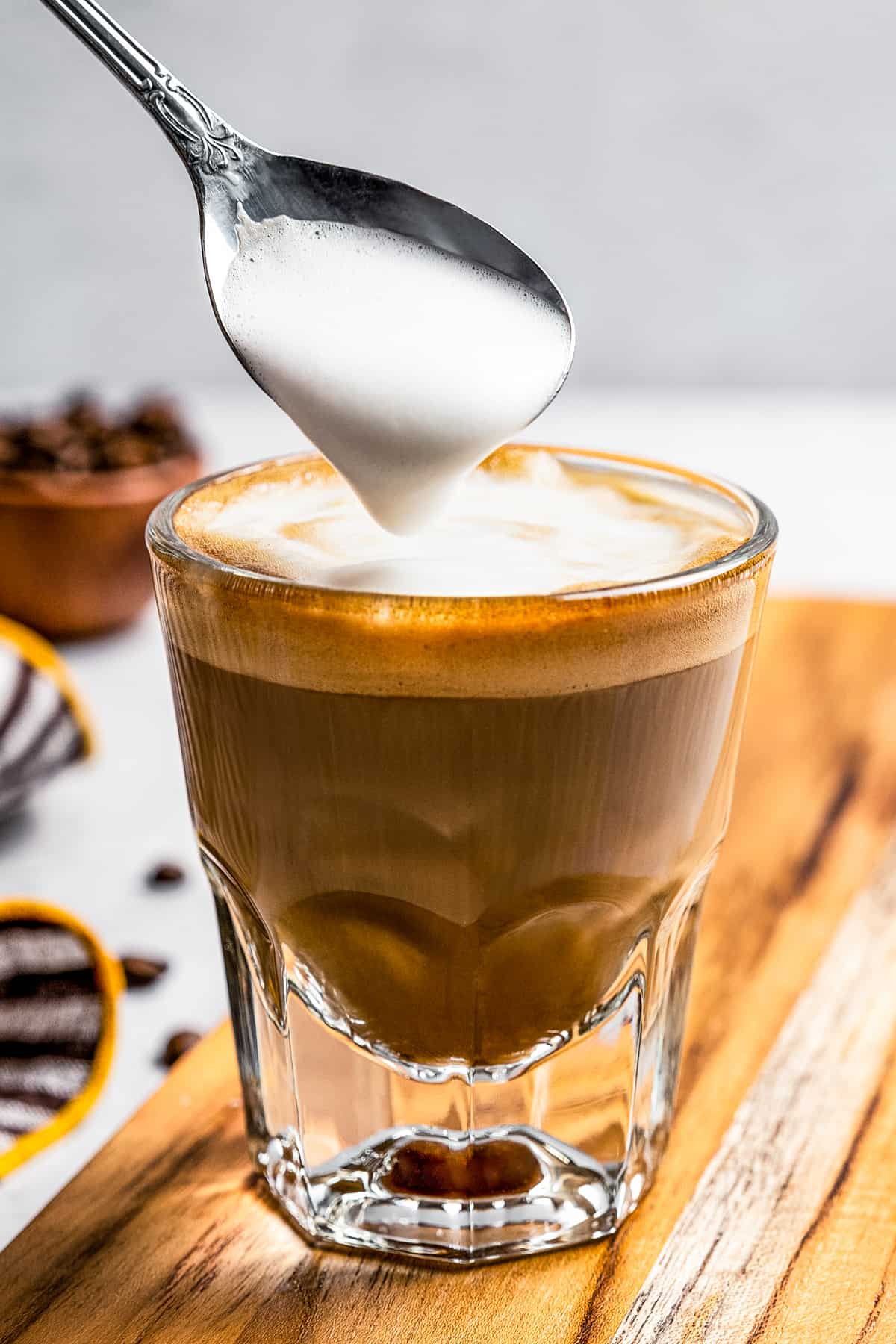 Spooning milk froth on top of a cortado drink