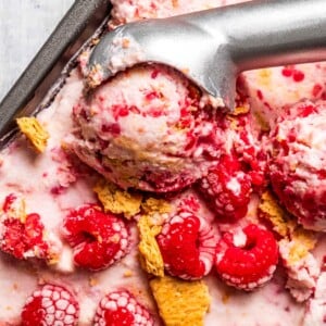 Taking a scoop of raspberry cottage cheese ice cream out of a loaf pan.