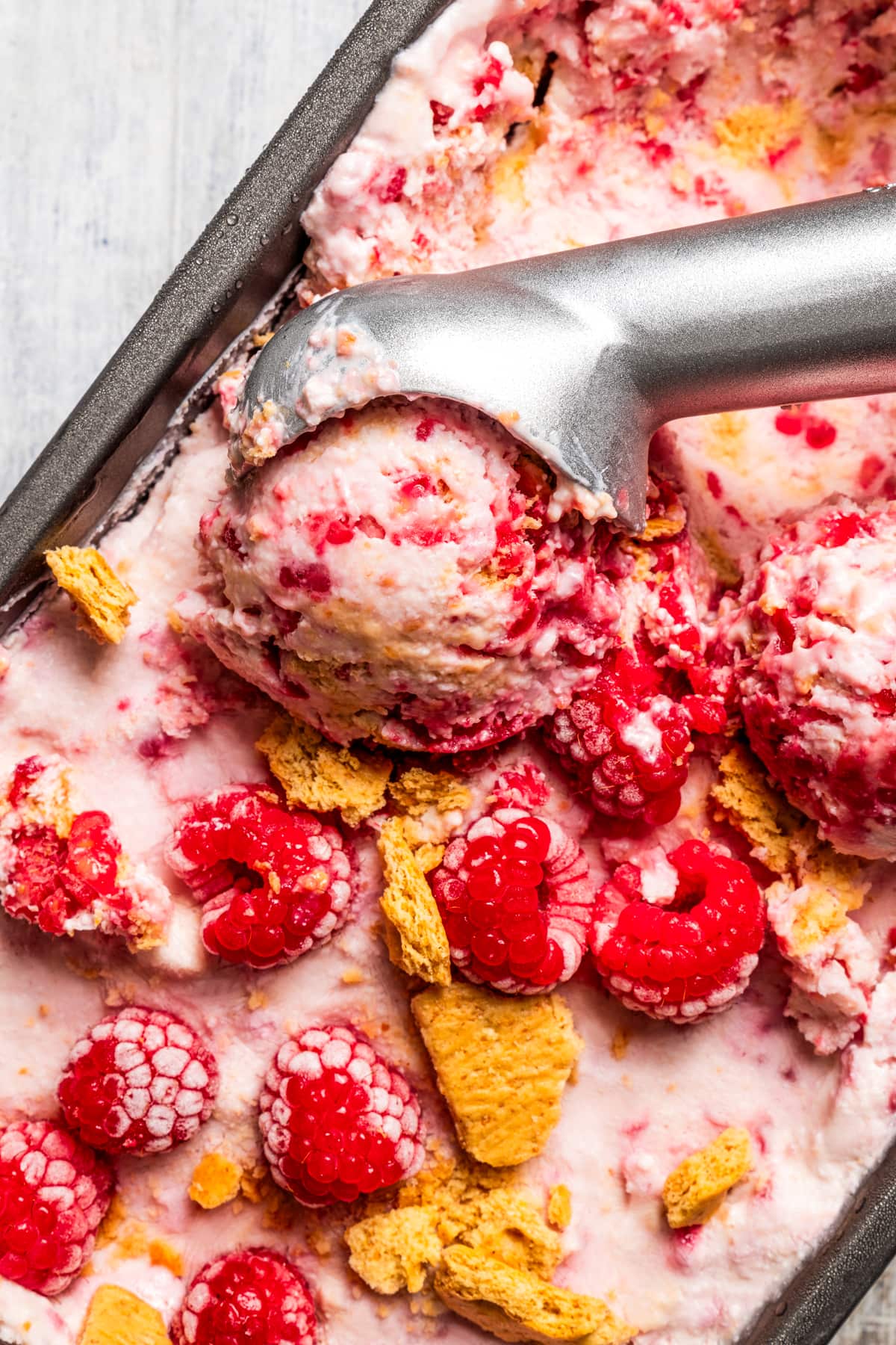 Taking a scoop of raspberry cottage cheese ice cream out of a loaf pan.