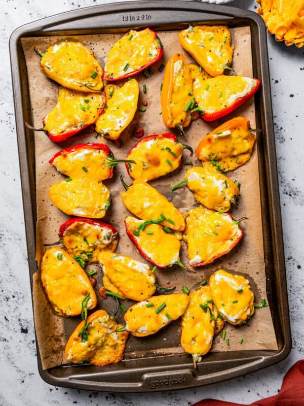 Baked cream cheese stuffed peppers on a lined baking sheet.