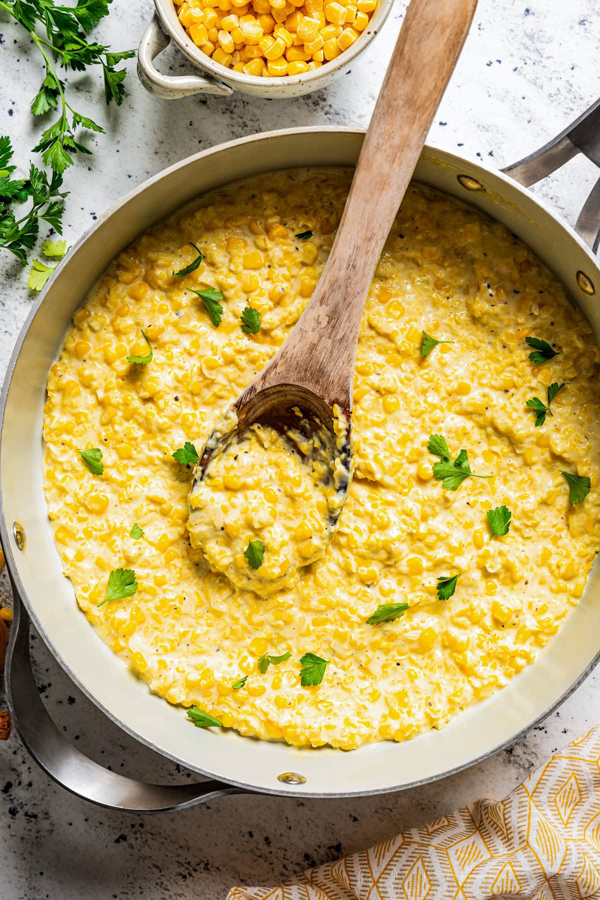 Stirring through corn in a skillet with cream and butter.