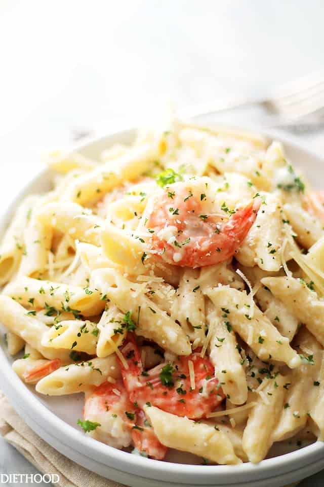 Lemon shrimp pasta in a white bowl topped with parmesan cheese and fresh minced parsley.