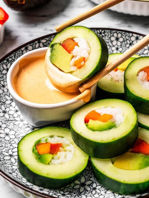 Dipping a slice of a cucumber roll in sriracha aioli.