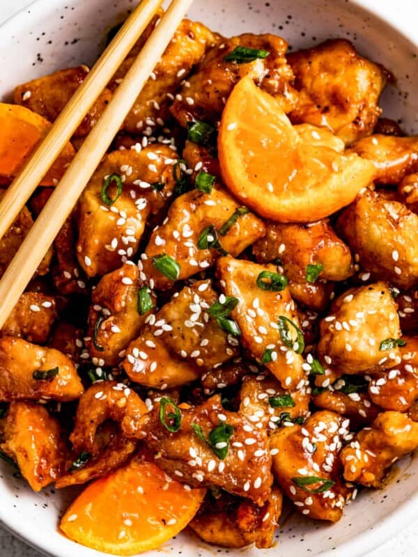 overhead shot of a bowl with mandarin chicken, and chopsticks set on top of the bowl.