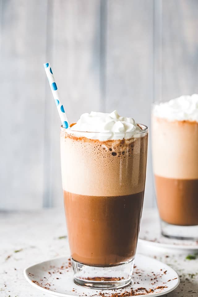 Two drinking glasses filled with iced coffee.