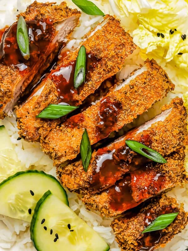 Pork Katsu cutlet served with katsu sauce, cucumber, rice, and salad.