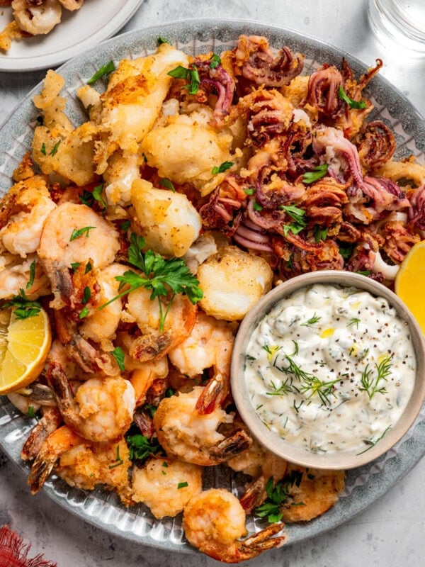 Fritto misto served on a round plate with a small bowl of tartar sauce.