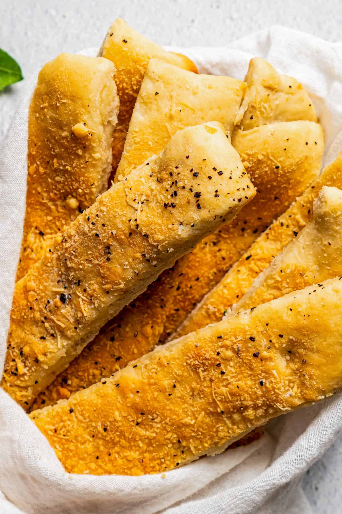 Up close photo of breadsticks wrapped with a white cloth.