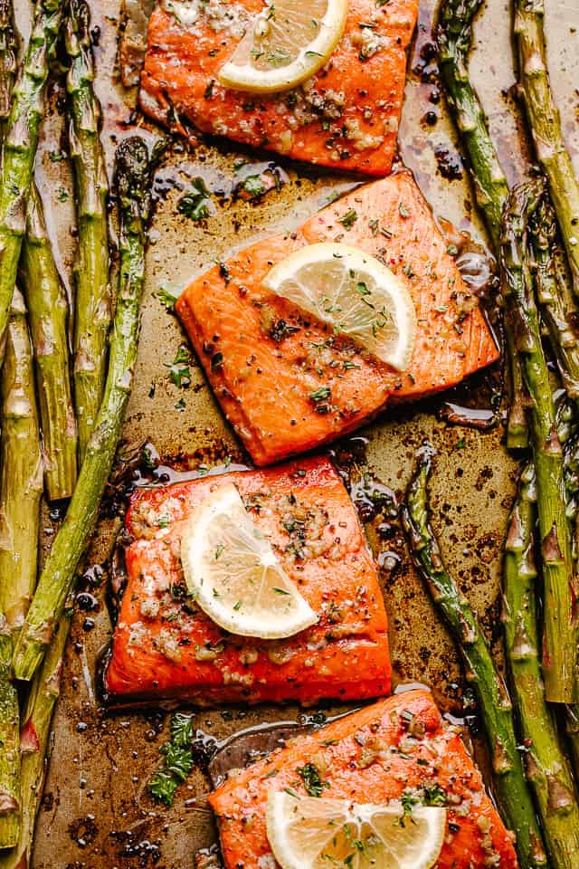 Roasted sockeye salmon fillets topped with lemon slices and asparagus spears on either side