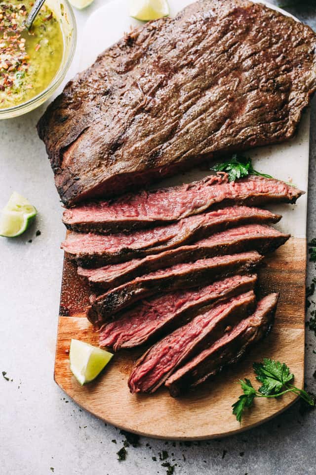 Sliced grilled flank steak on a cutting board.