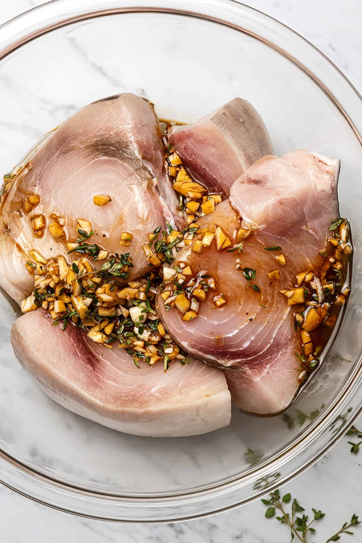 Raw swordfish marinating in a glass bowl